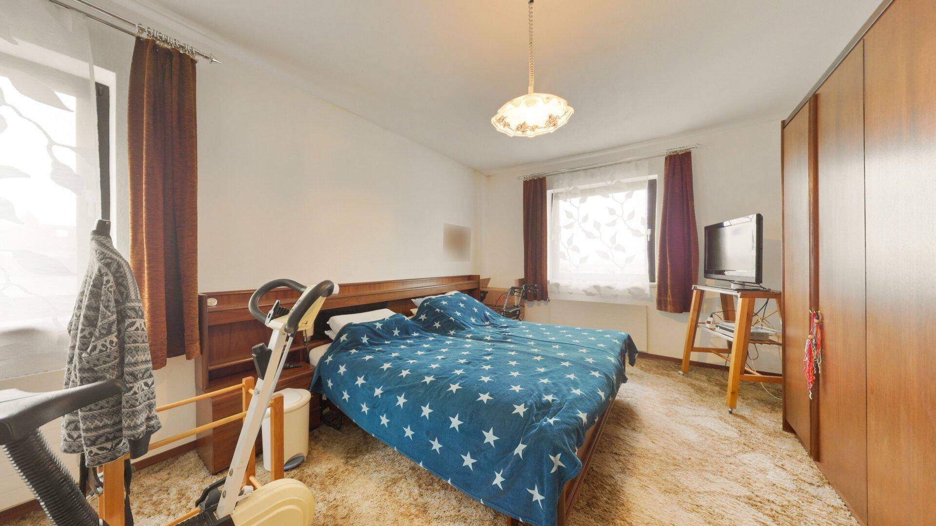Schlafzimmer mit Doppelbett, Teppichboden und Holzschränken, bietet eine gemütliche Atmosphäre.