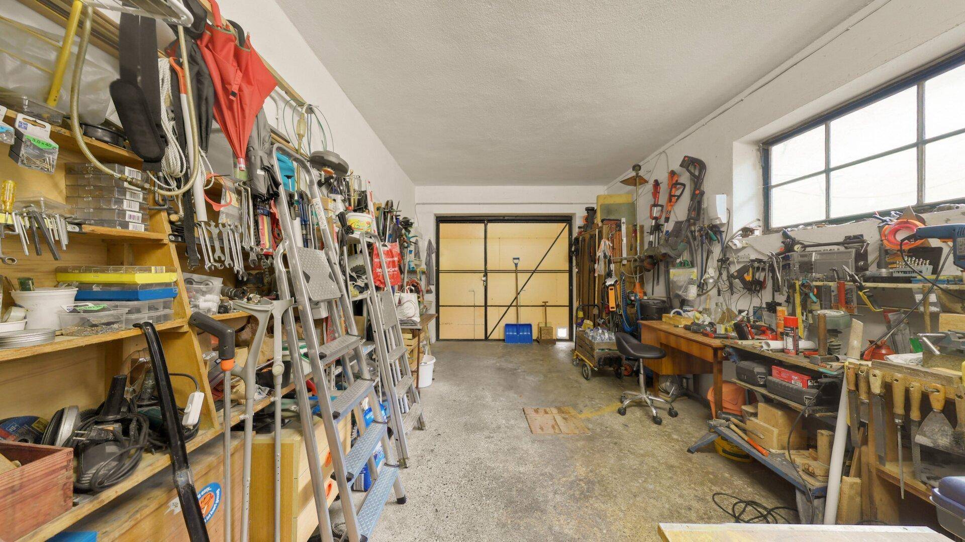 Geräumige Werkstatt mit vielen Regalen und Arbeitsflächen, ideal für Heimwerkerprojekte und Lagerung.