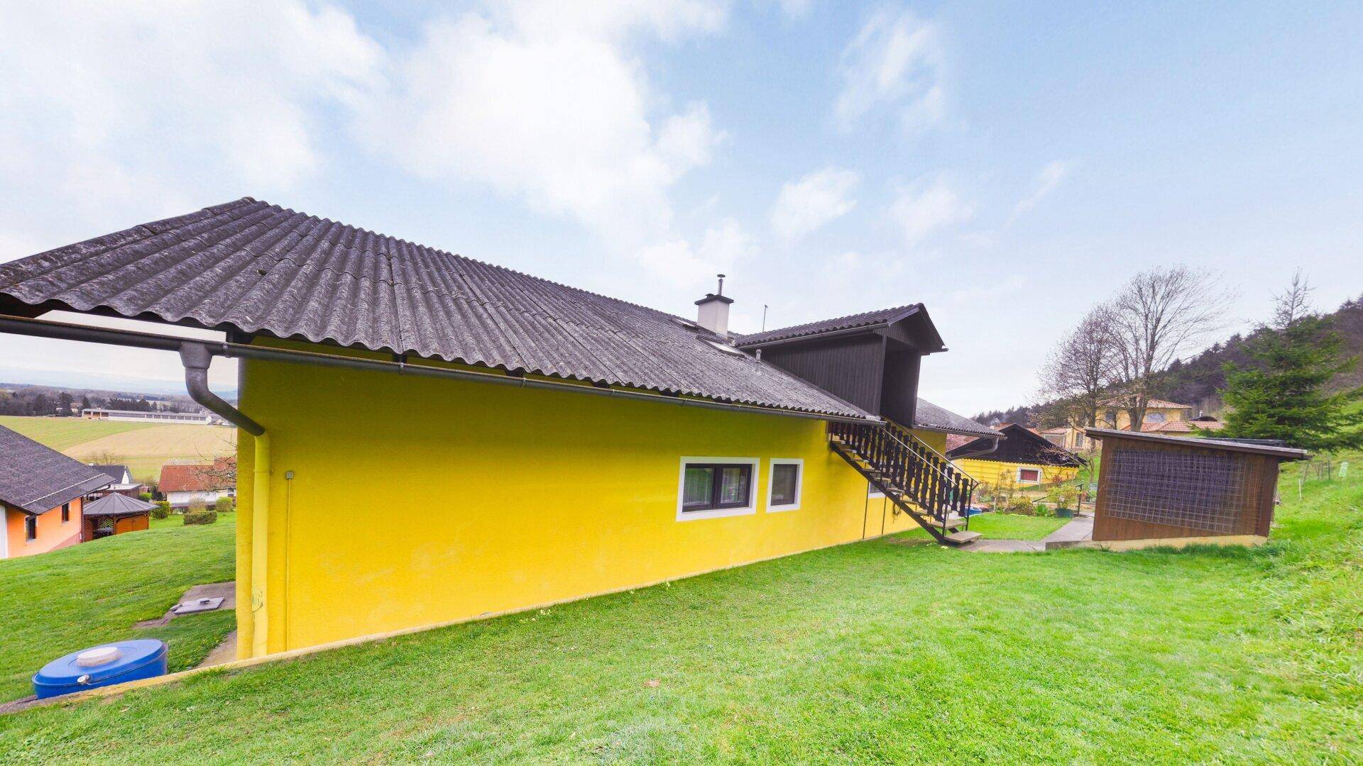 Rückansicht des Hauses mit großem Garten und Blick auf die umliegende Landschaft.