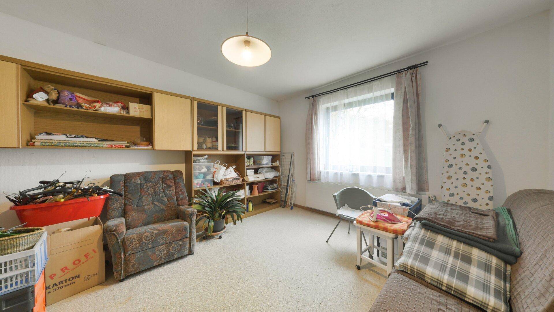 Geräumiger Raum mit Teppichboden und Wandregalen, vielseitig nutzbar als Hobby- oder Abstellzimmer.