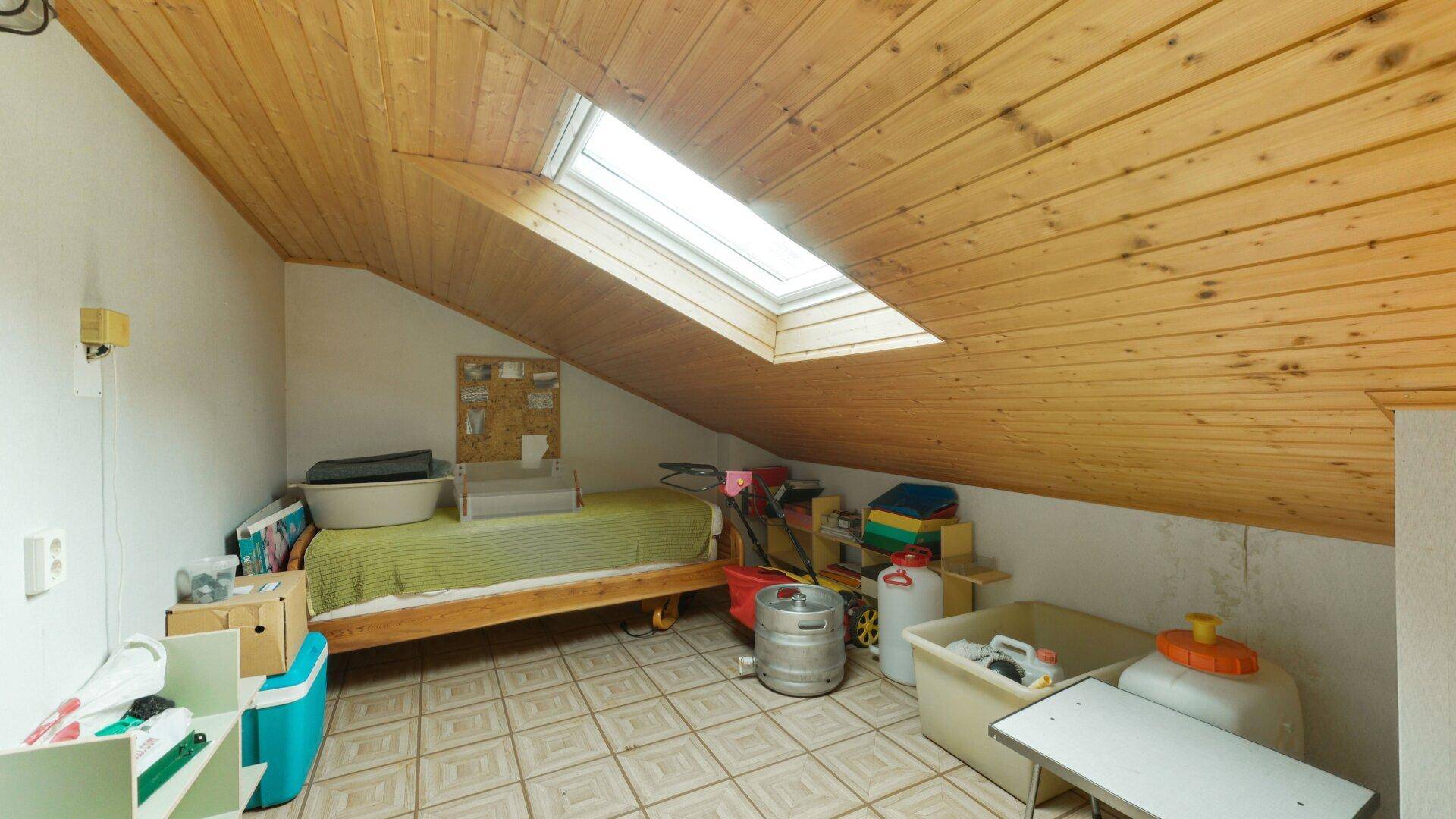 Ausgebautes Dachzimmer mit Holzverkleidung und Dachfenster, vielseitig nutzbar als Schlaf- oder Hobbyraum.