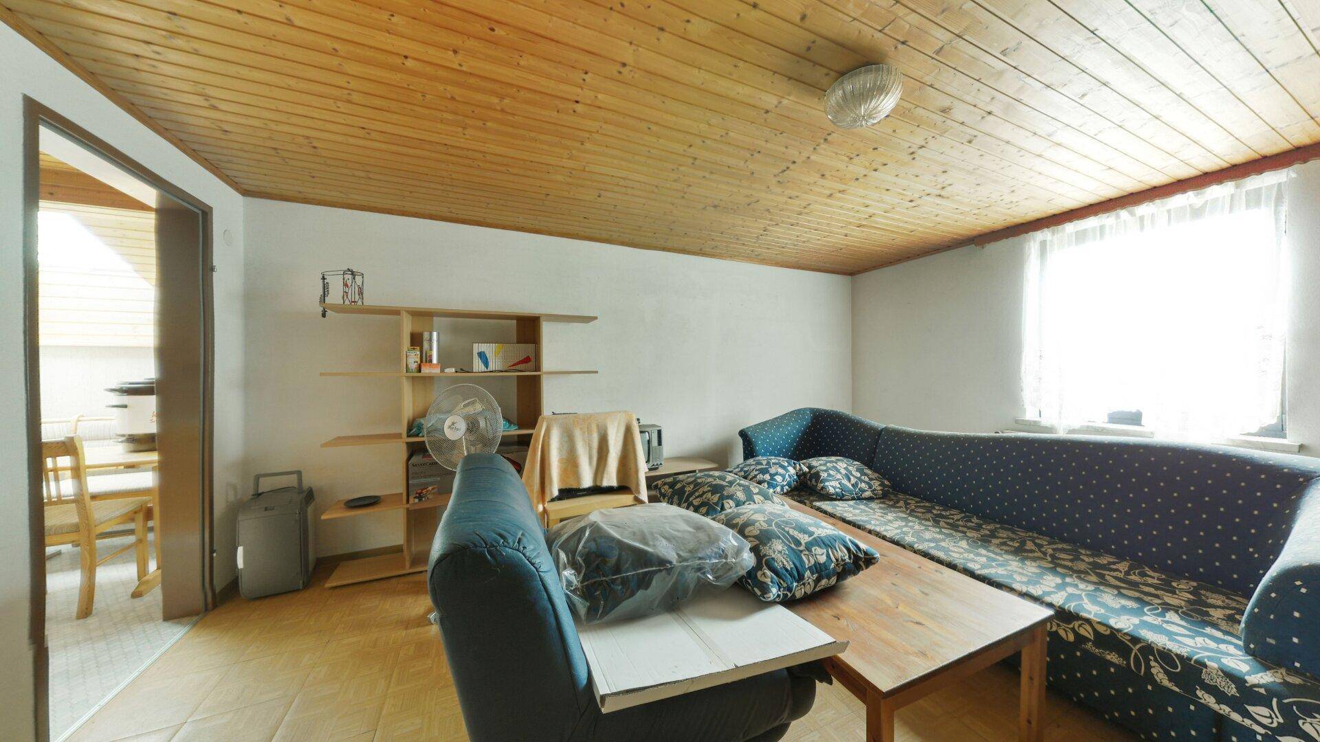 Gemütliches Wohnzimmer mit Holzdecke und großem Sofa, bietet Platz zum Entspannen.