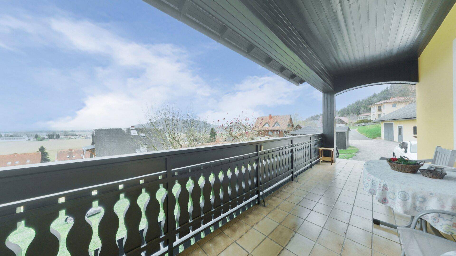 Langer Balkon mit Fliesenboden und traditionellem Geländer, bietet weite Aussicht auf die Landschaft.