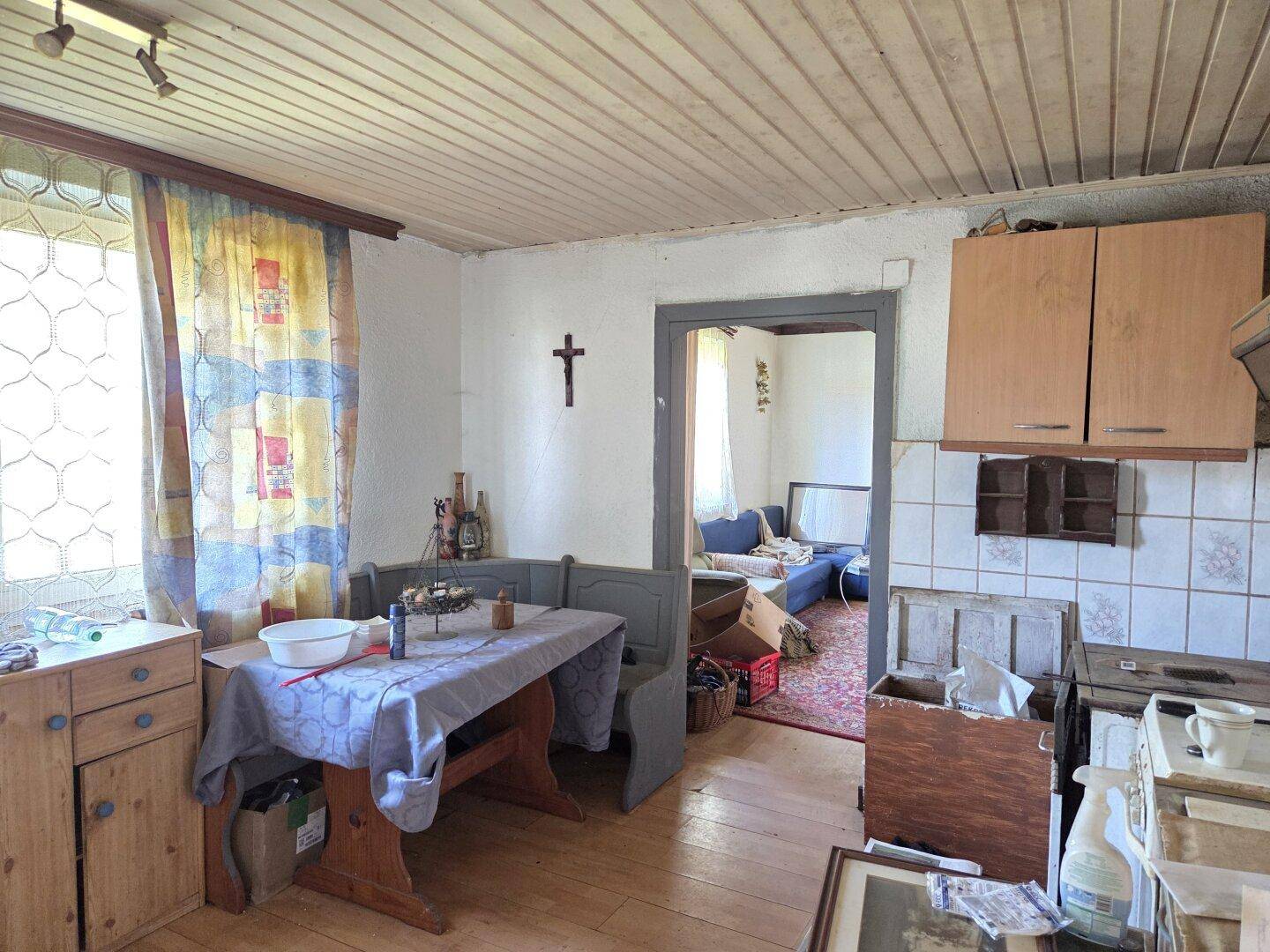 Rustikaler Essbereich mit Holztisch, Eckbank und Durchgang zu einem weiteren Wohnraum.