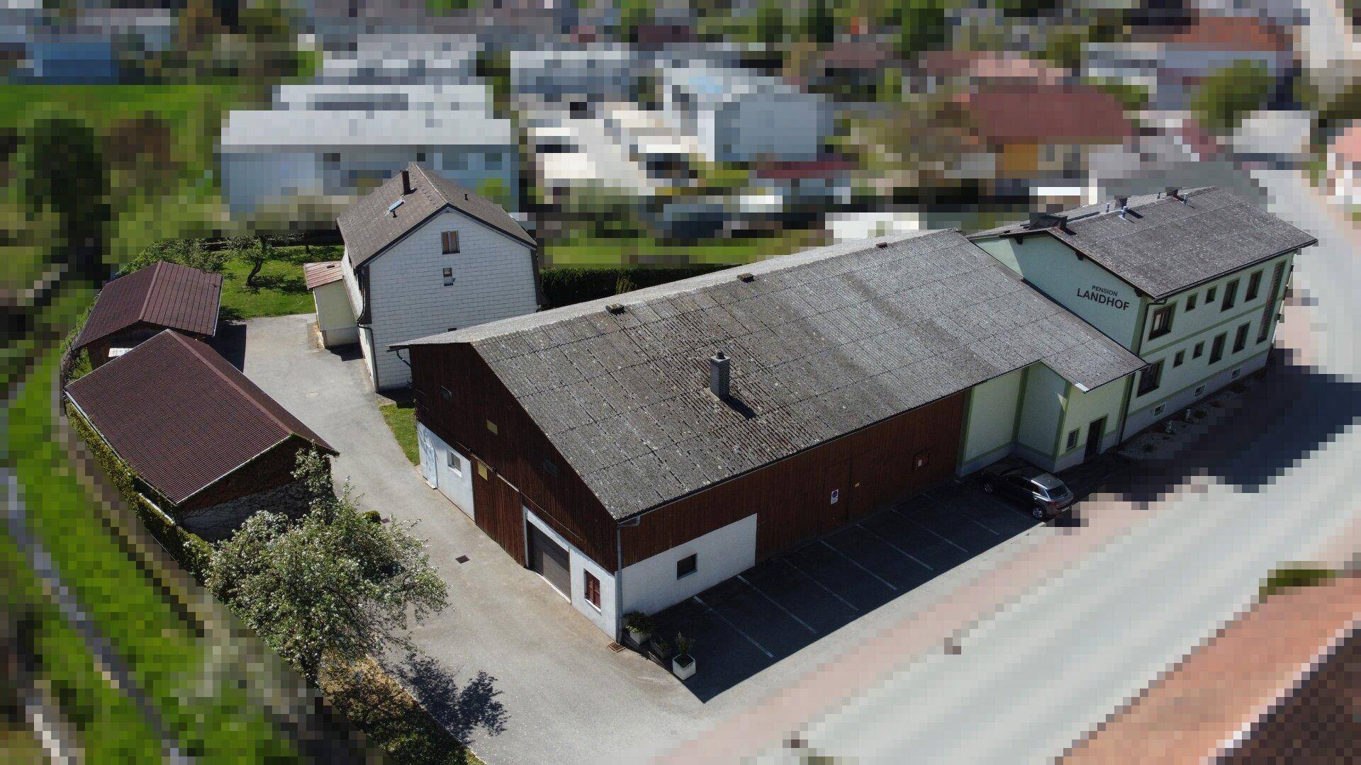 Gesamtansicht des Anwesens mit mehreren Gebäuden, großem Parkplatz und ländlicher Umgebung.