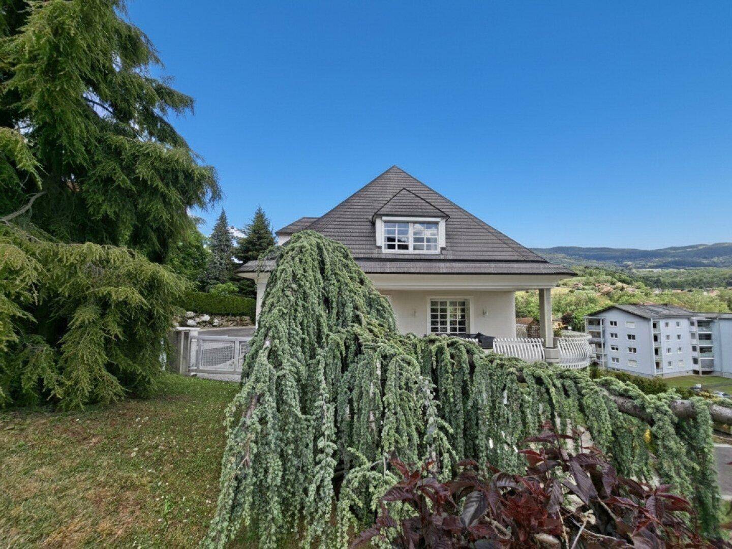 Seitliche Ansicht der Villa mit üppiger Vegetation und weitem Blick über die hügelige Landschaft.