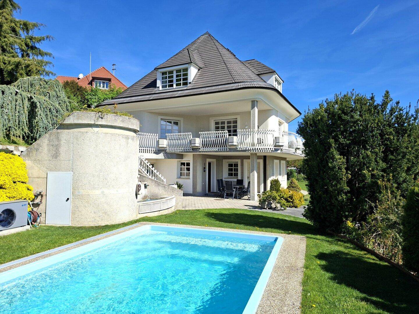 Rückseite der Villa mit großem Pool, Sonnenterrasse und Treppenanlage im gepflegten Gartenbereich.