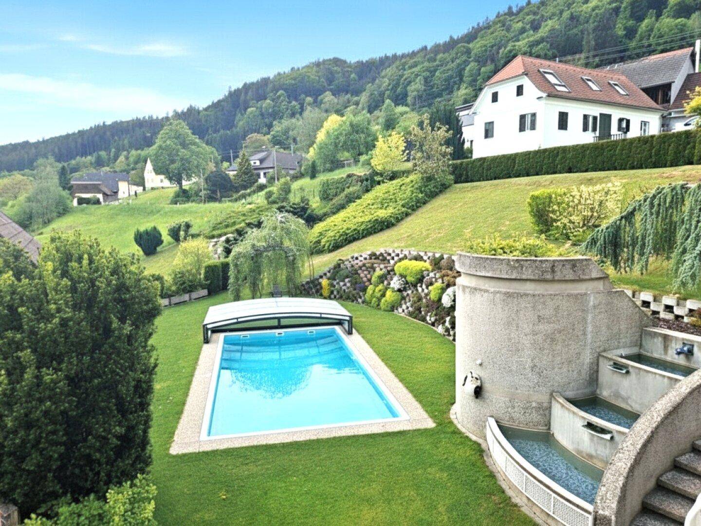 Weitläufiger Gartenbereich mit großem Pool und malerischem Blick auf die umliegende grüne Hügellandschaft.