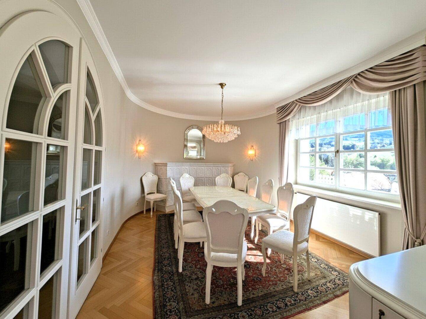 Eleganter Essbereich mit großem Esstisch, Kronleuchter und Fenstern mit weitem Ausblick.