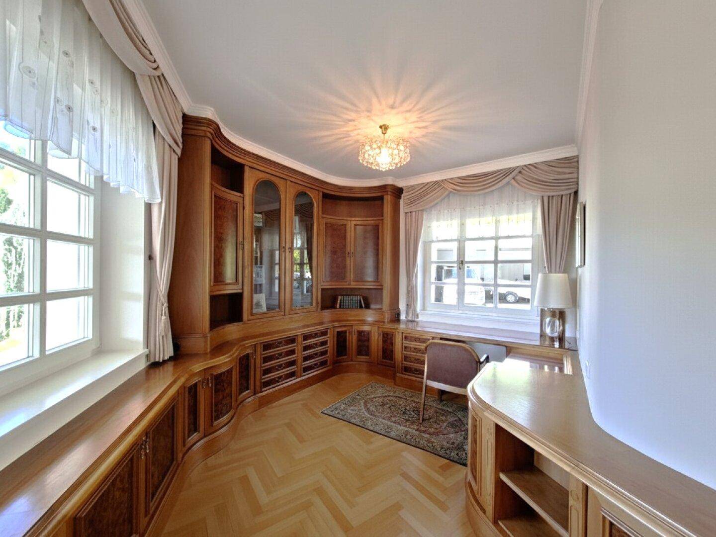 Stilvolles Arbeitszimmer mit maßgefertigten Holzregalen, Schreibtisch und großen Fenstern.