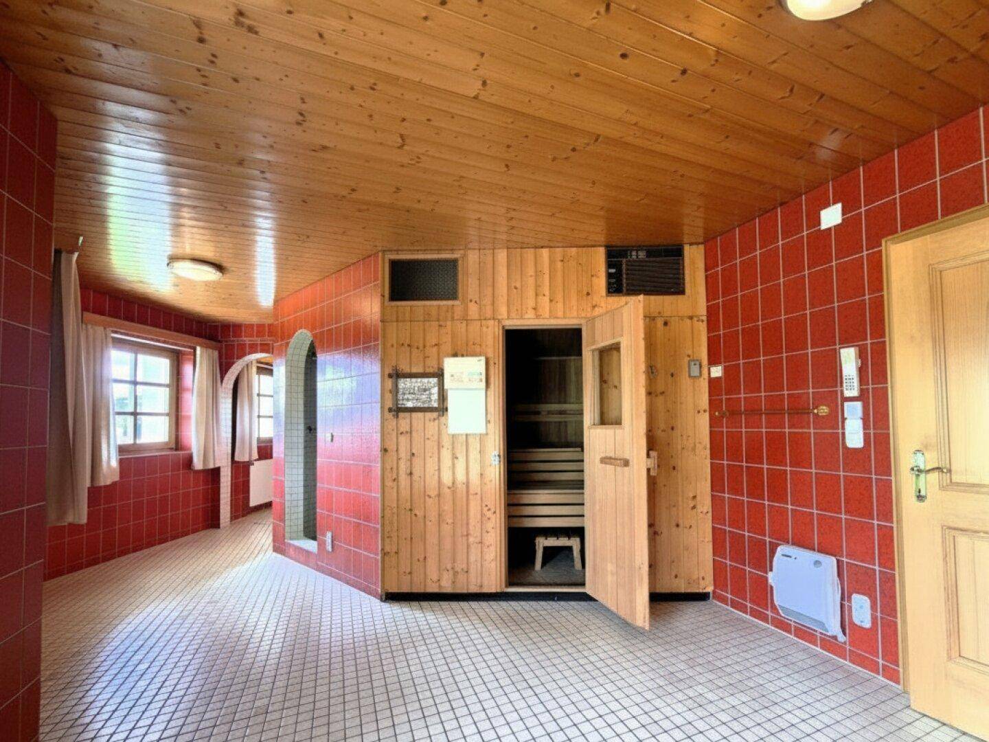 Wellnessbereich mit Sauna, roten Fliesen und Holzdecke für entspannende Stunden.