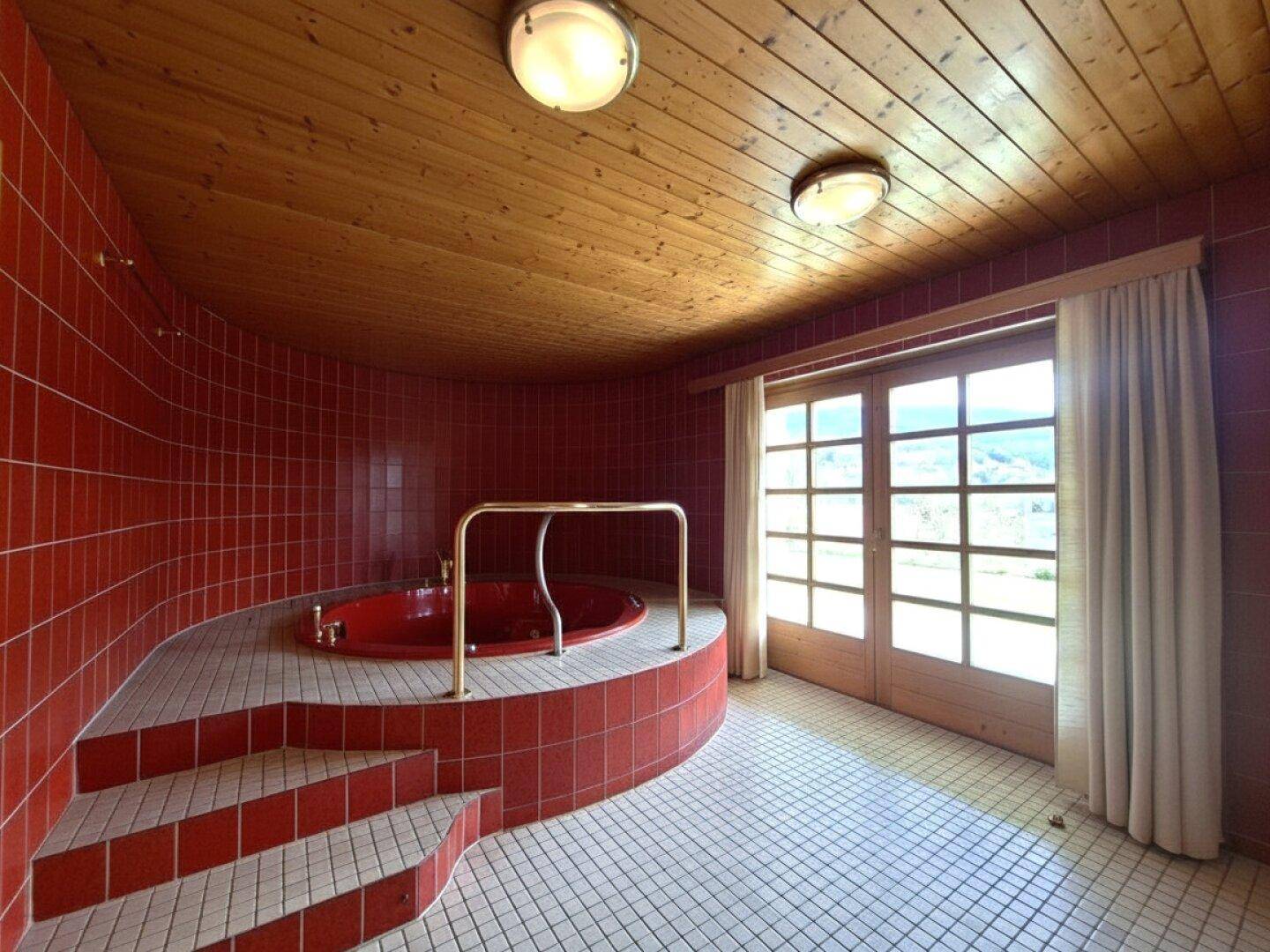 Entspannungsbereich mit Whirlpool, roten Fliesen und Zugang zu einem Balkon mit Aussicht.