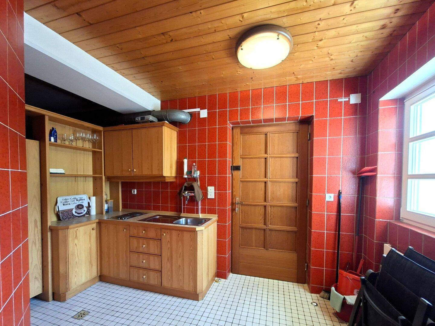 Kleine Küchenzeile mit Spüle und Holzschränken im Wellness- oder Barbereich.