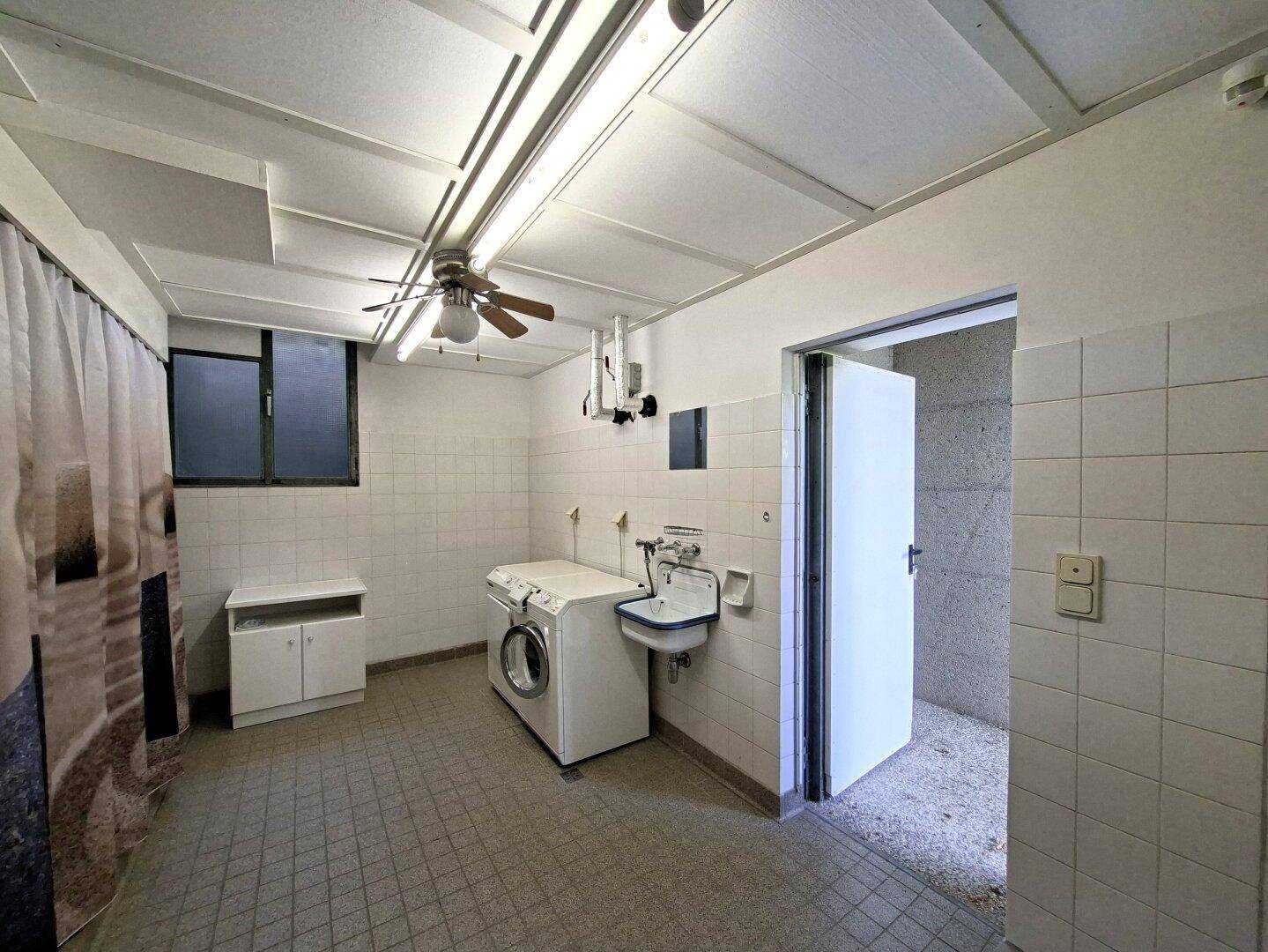 Praktischer Hauswirtschaftsraum mit Waschmaschine, Spülbecken und Fliesenboden.