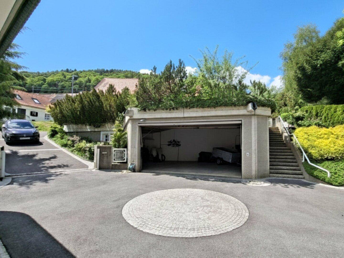 Geräumige Doppelgarage mit Auffahrt und begrüntem Dach, eingebettet in die Landschaft.