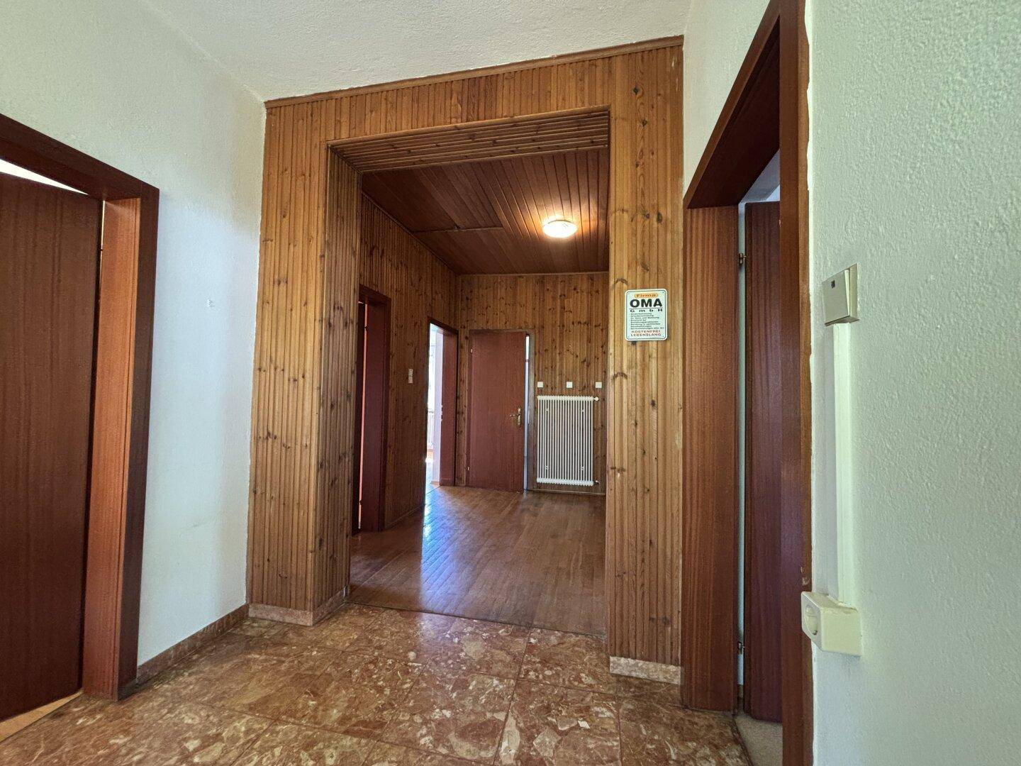 Flur mit Holzvertäfelung und Terrakotta-Fliesenboden, führt zu weiteren Räumen.