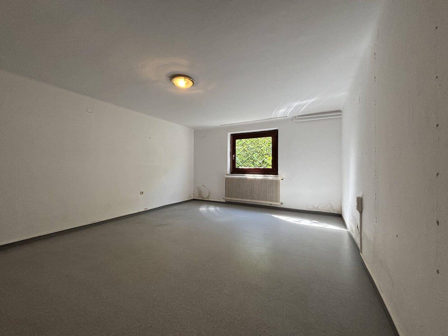 Kellerraum mit grauem Boden und kleinem Fenster, bietet zusätzlichen Stauraum.