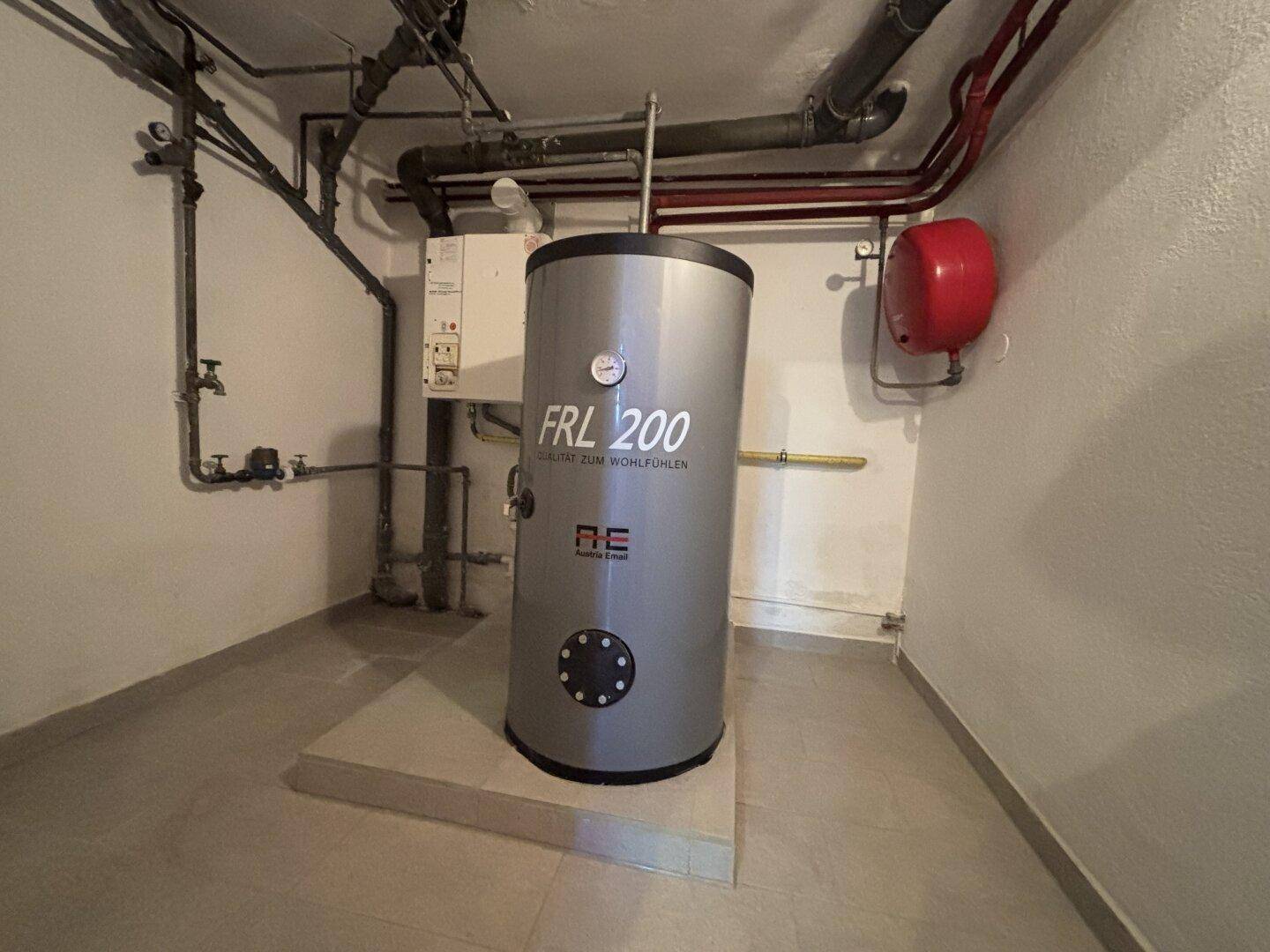 Heizungsraum mit Warmwasserspeicher und technischen Installationen im Keller.