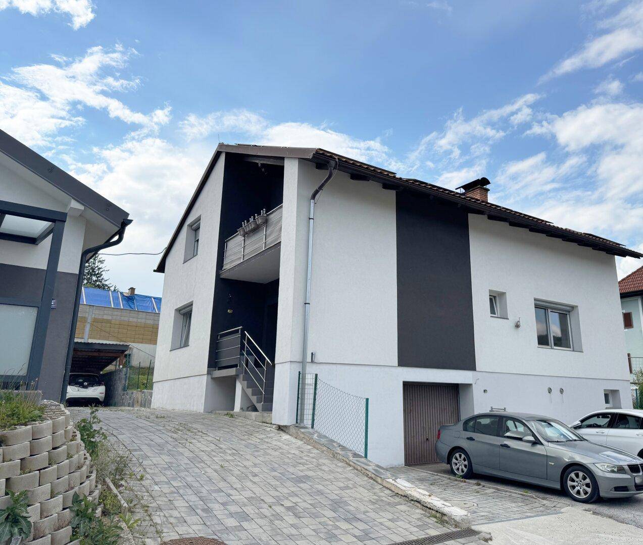 Vorderansicht des Hauses mit Zufahrt, Garage und Balkon, modern gestaltet und gepflegt.
