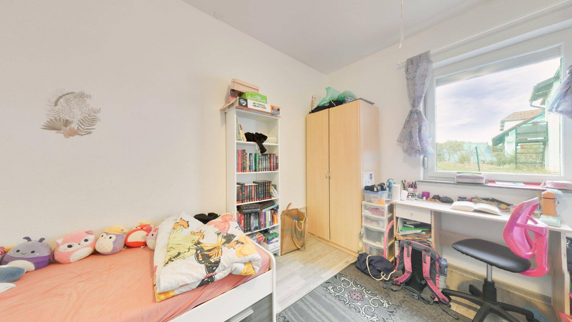 Kinderzimmer mit Bett, Schreibtisch und Bücherregal, hell und funktional eingerichtet.