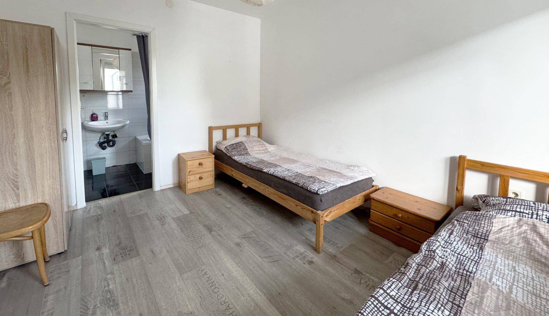Schlafzimmer mit zwei Einzelbetten und direktem Zugang zu einem kleinen Badezimmer.
