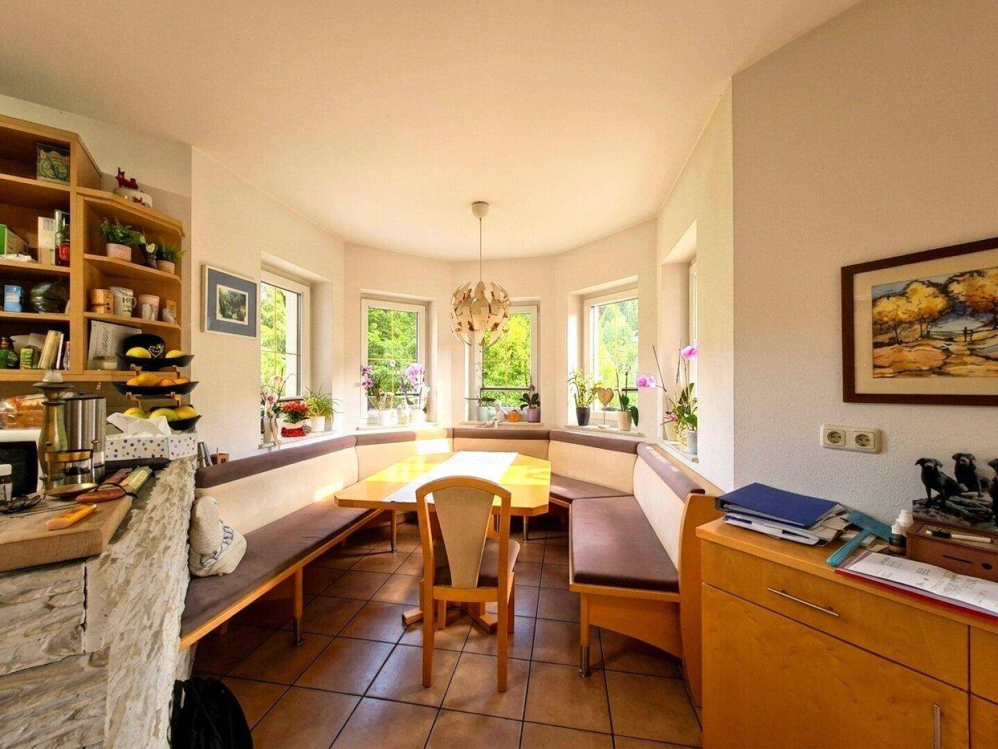 Gemütlicher Essbereich in der Küche mit Eckbank, Holztisch und viel Tageslicht durch die Fenster.