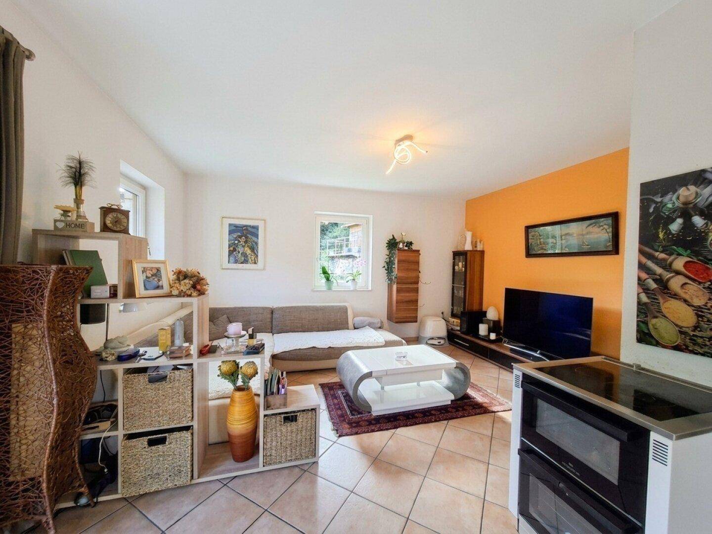 Wohnzimmer mit Fliesenboden, orangefarbener Akzentwand und modernen Möbeln.