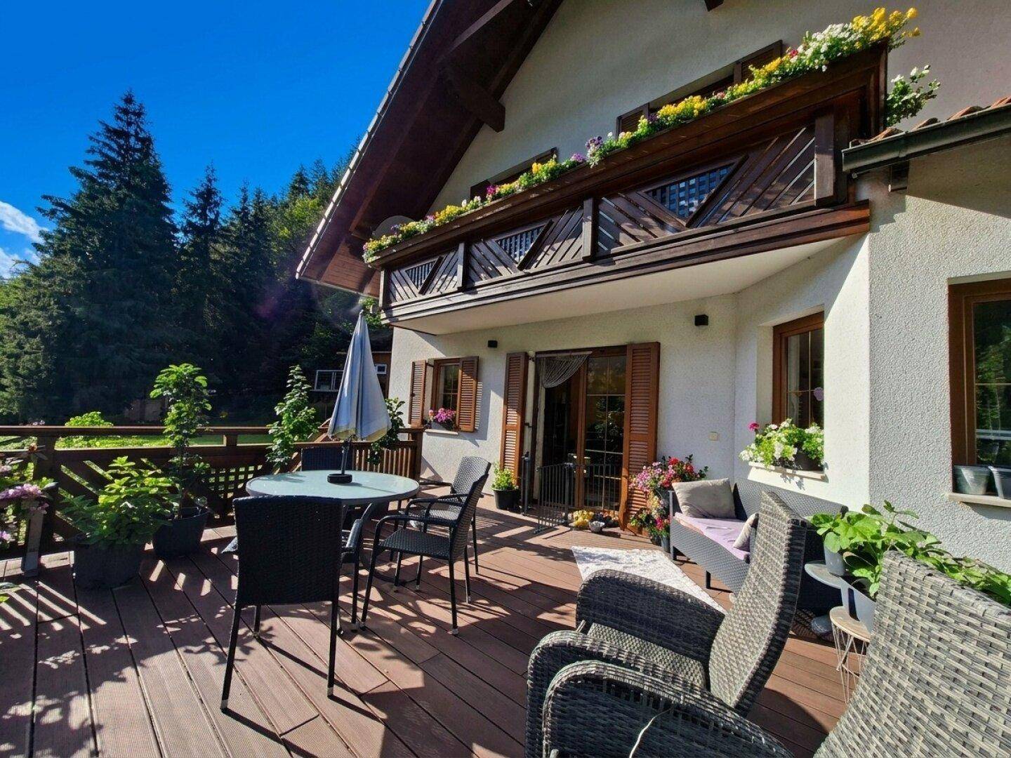 Große Holzterrasse mit Gartenmöbeln und Blumenkästen, ideal zum Entspannen im Freien.