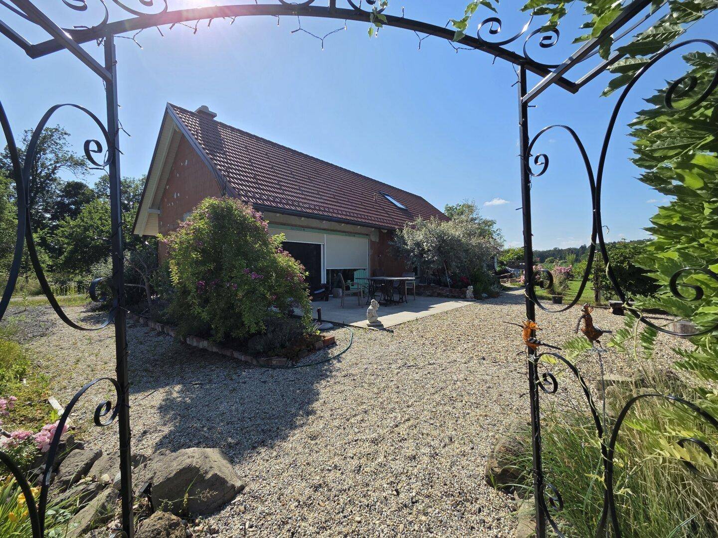 Kiesgartenbereich mit dekorativem Tor und Blick auf das Landhaus.