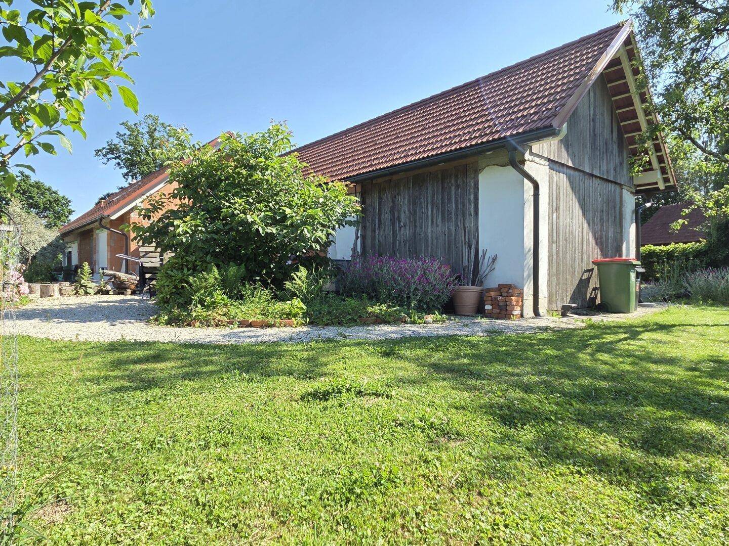 Gepflegter Garten mit Rasen, Sträuchern und Blick auf die Holzfassade des Hauses.