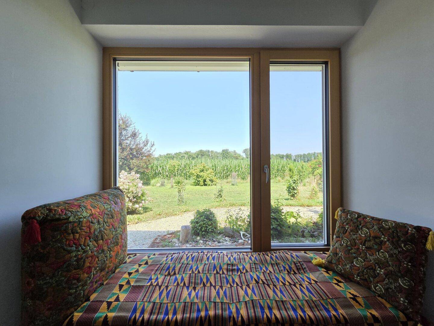 Gemütliche Fensternische mit Sitzbank und weitem Blick über die Felder.