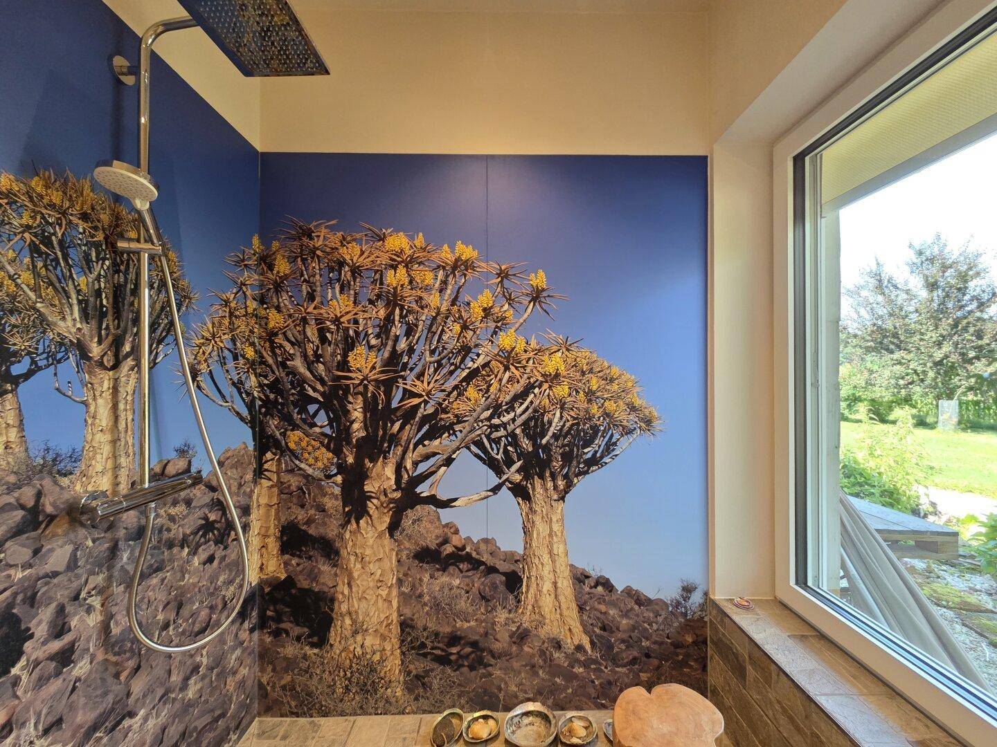 Duschbereich mit exotischer Wandgestaltung und großem Fenster zum Garten.