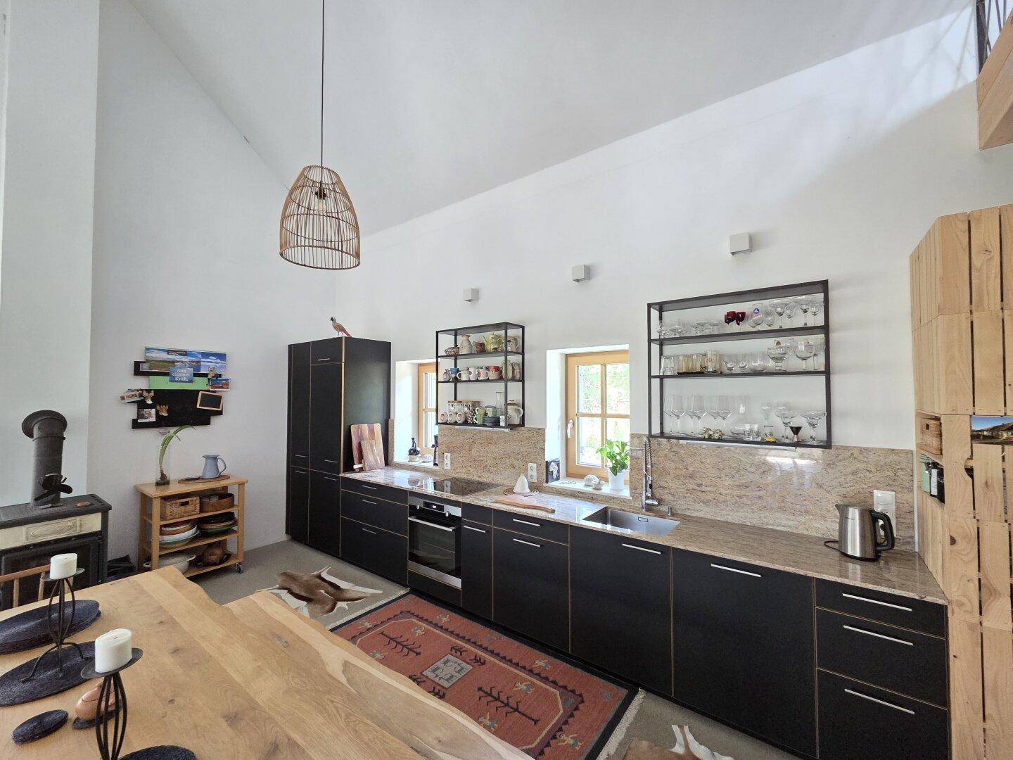 Moderne Küche mit schwarzen Schränken, Granitarbeitsplatten und hohen Decken.