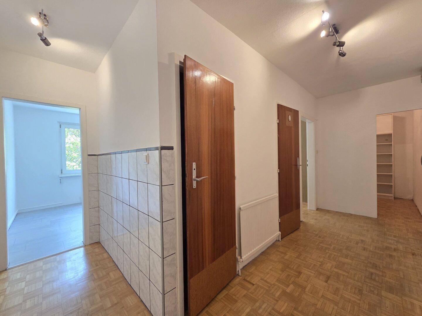 Geräumiger Flur mit Parkettboden und Holztüren, der zu weiteren Räumen führt.