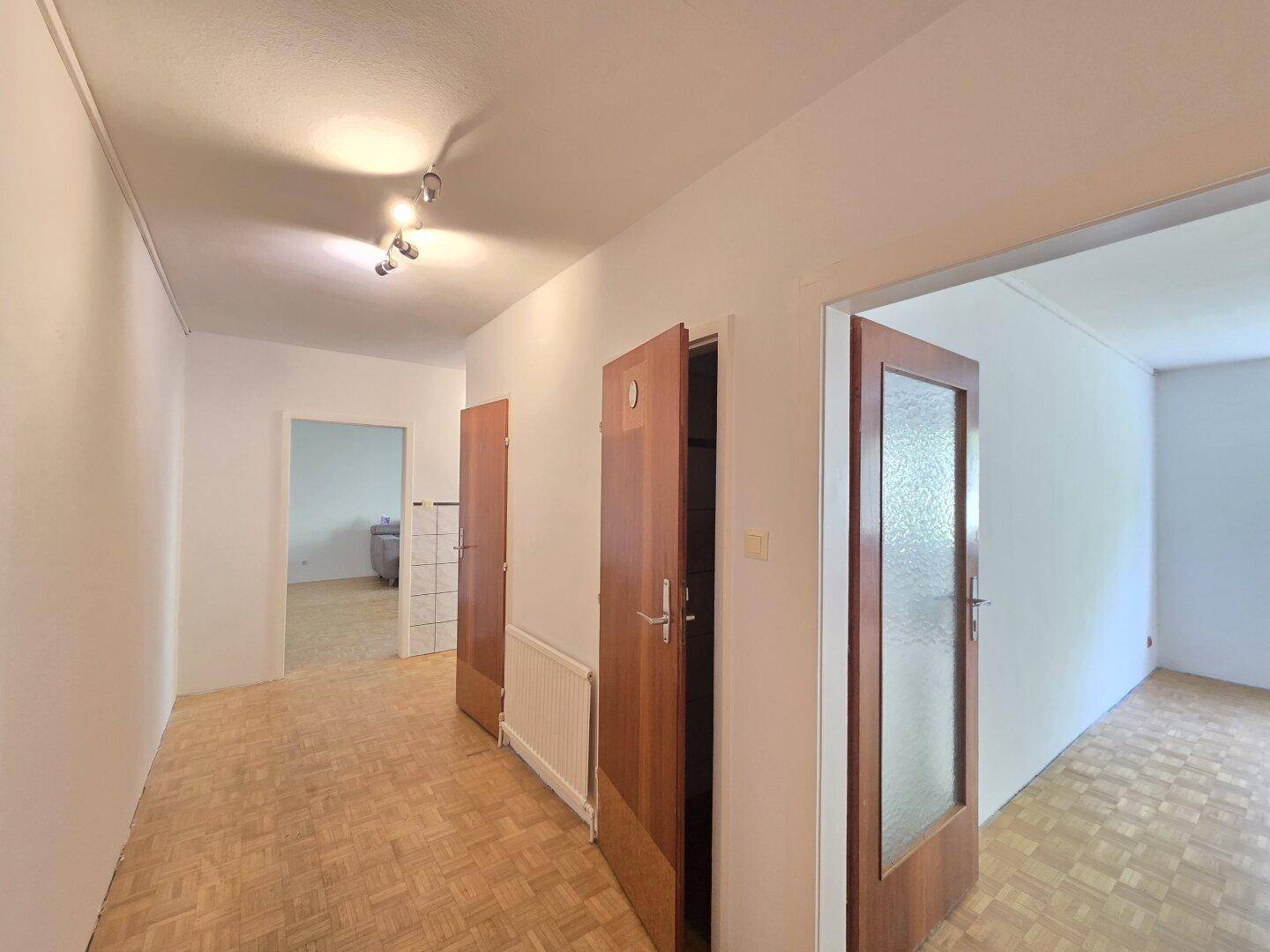 Heller Flur mit Parkettboden und Zugang zu verschiedenen Zimmern der Wohnung.