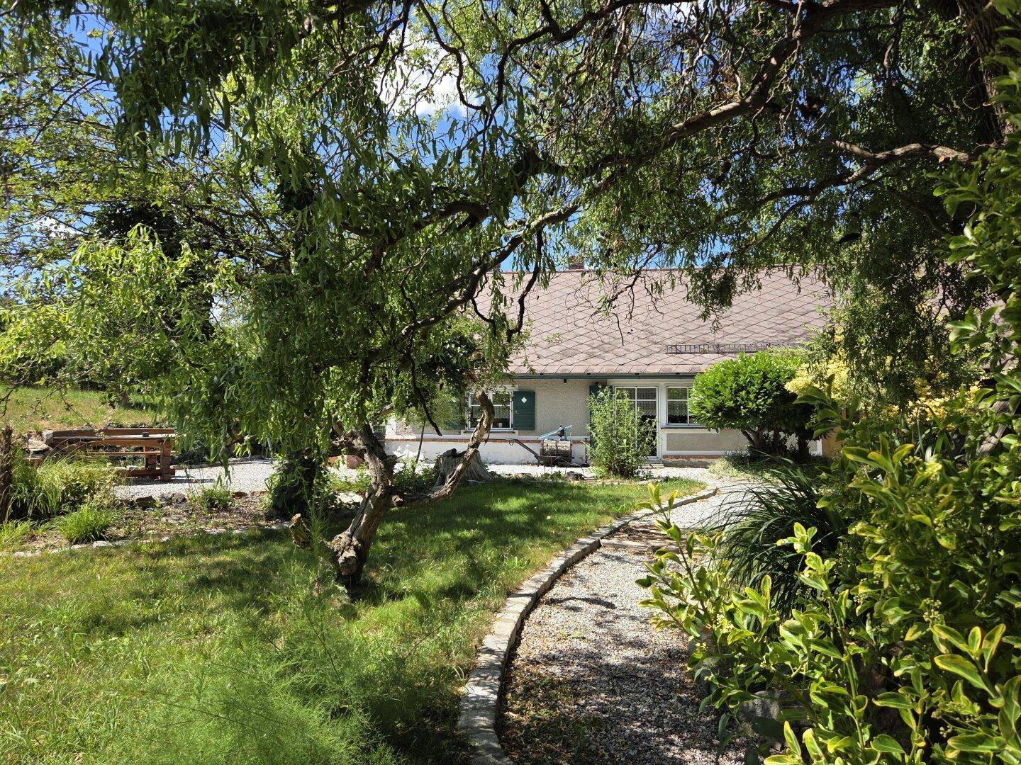 Malerischer Gartenweg führt durch üppiges Grün zum charmanten Landhaus.