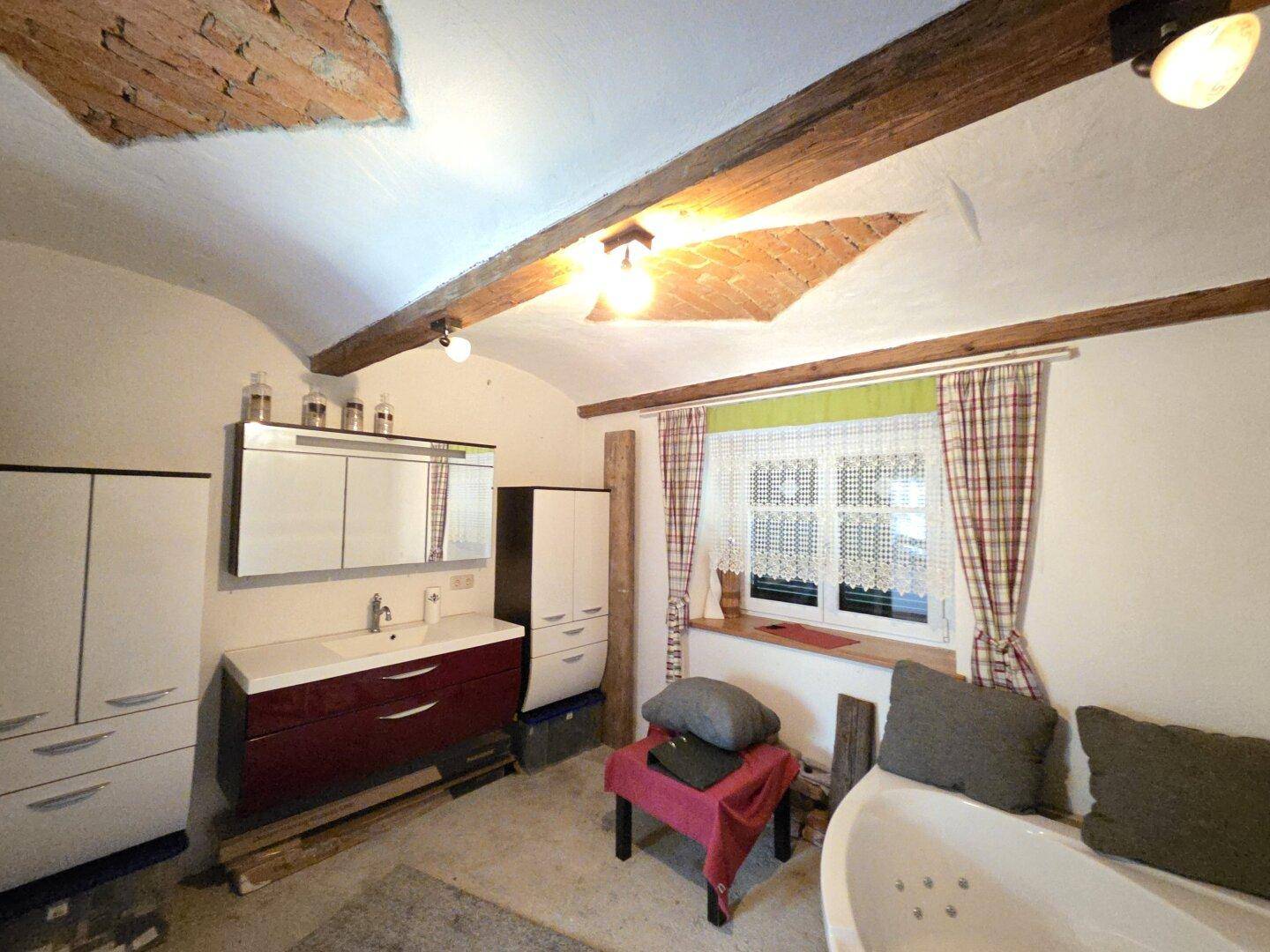 Modernisiertes Badezimmer mit Waschtisch, Badewanne und sichtbaren Deckenbalken.