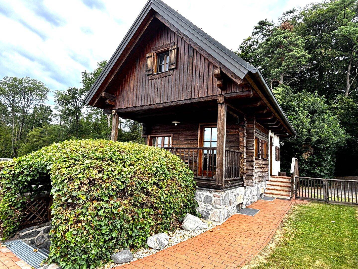 Charmantes Holzhaus mit traditioneller Architektur, umgeben von üppigem Grün und einem gepflegten Gartenbereich.