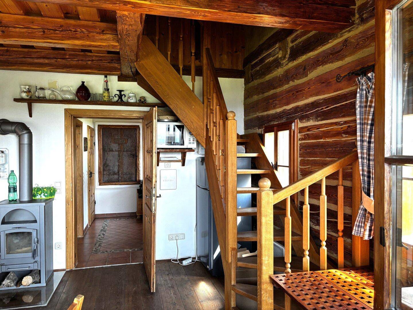 Offener Wohnbereich mit Holztreppe, die in das Obergeschoss führt, und Blick auf die Küche.