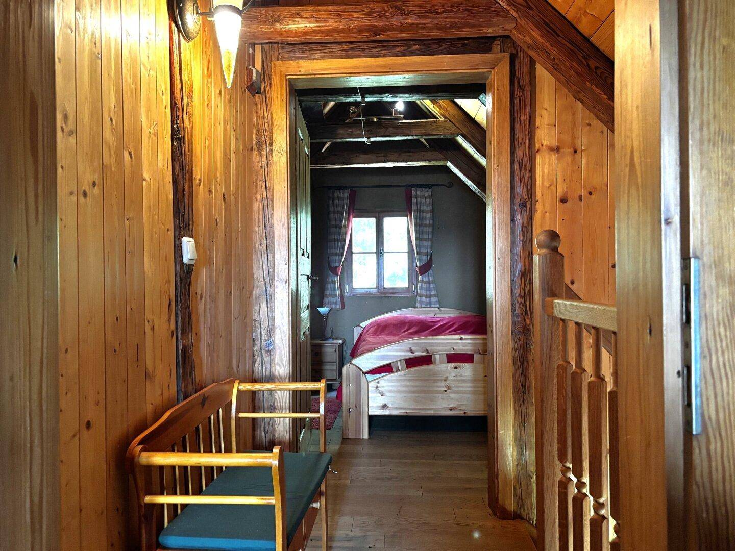 Hölzerner Flur im Obergeschoss mit Sitzbank, der zu einem gemütlichen Schlafzimmer führt.