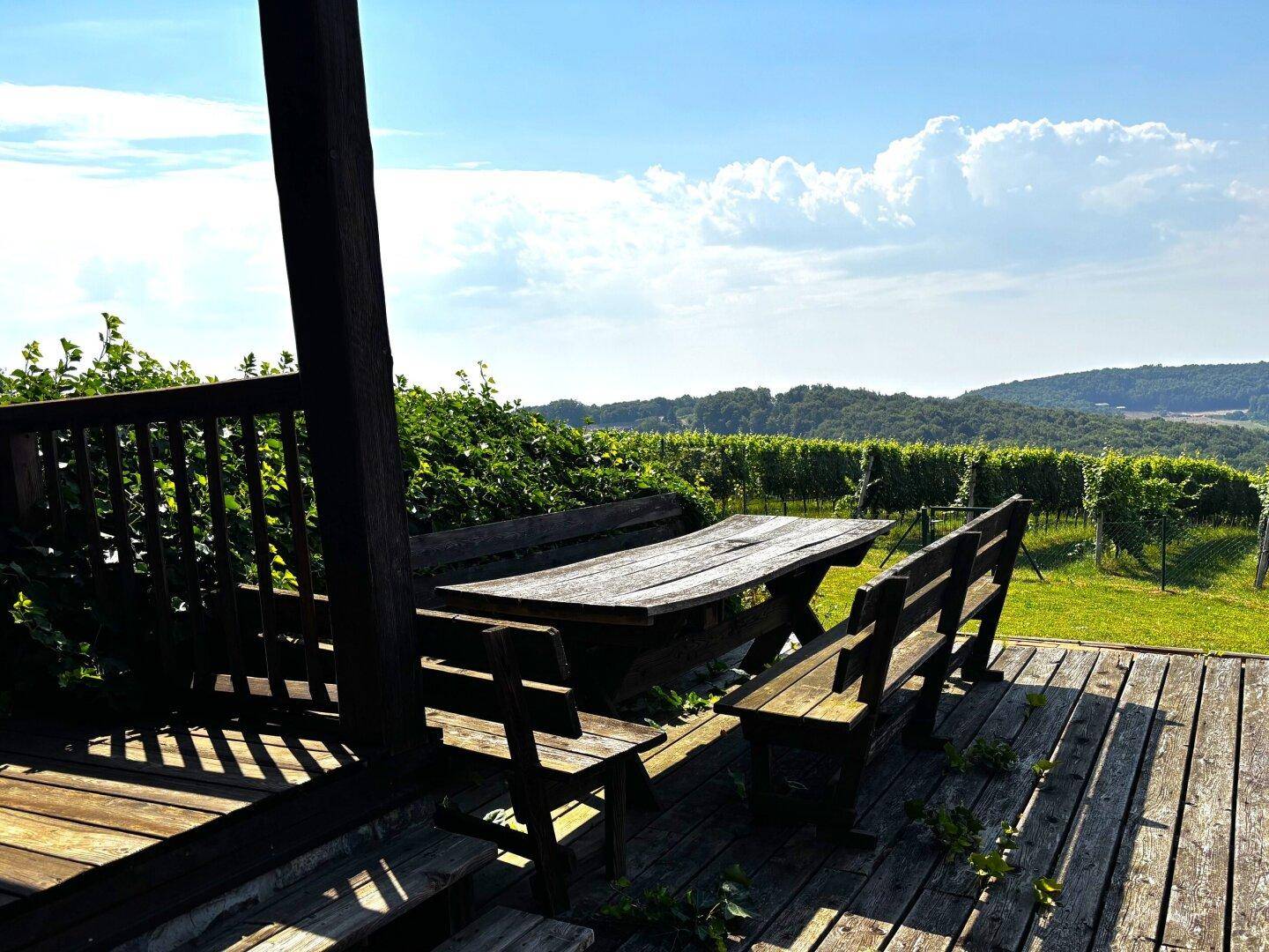 Gemütlicher Essbereich im Freien auf einer Holzterrasse mit Blick auf die umliegenden Weinberge.