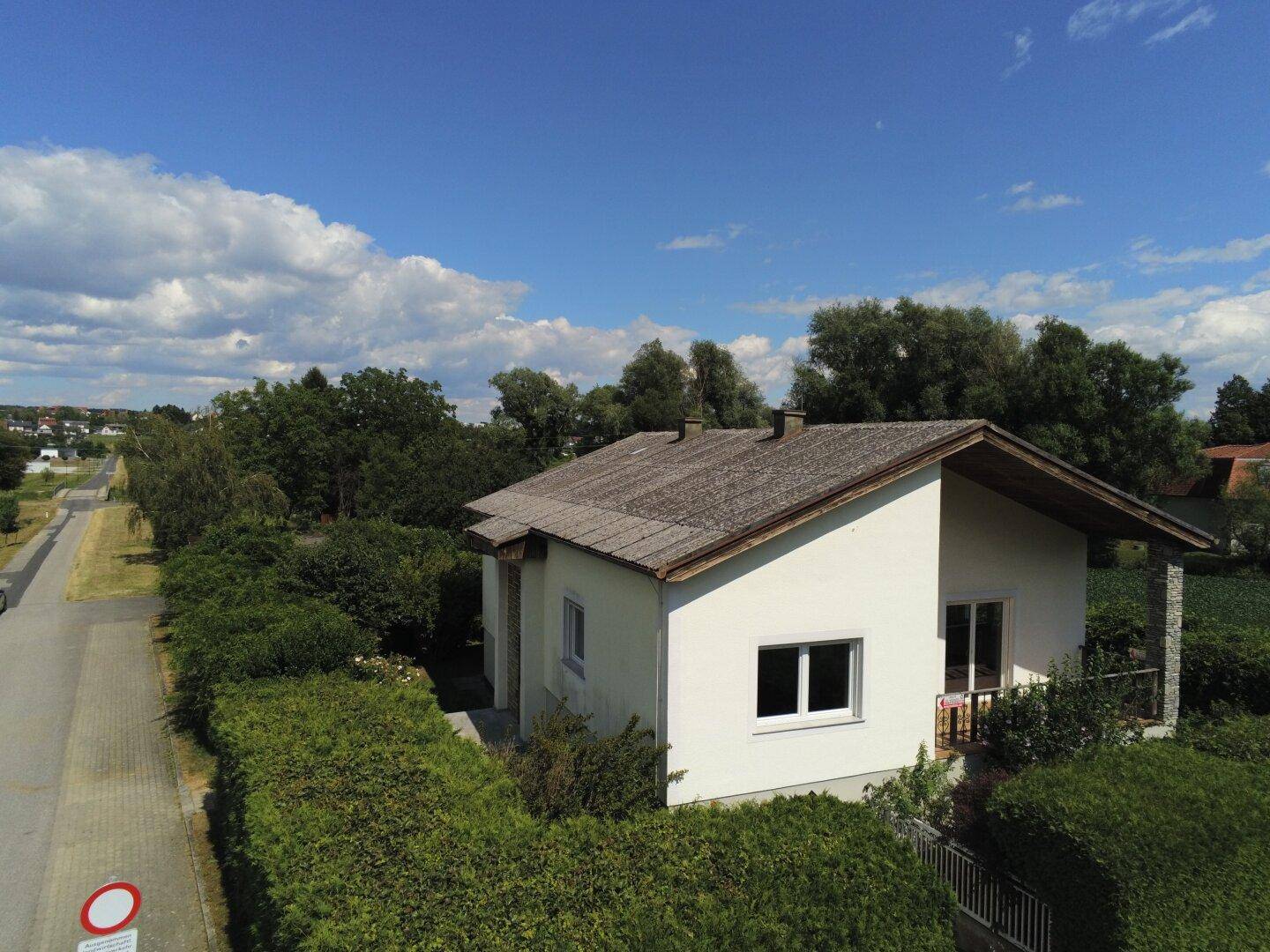 Hausansicht von oben mit kleinem Balkon, gepflegter Hecke und angrenzender Straße.