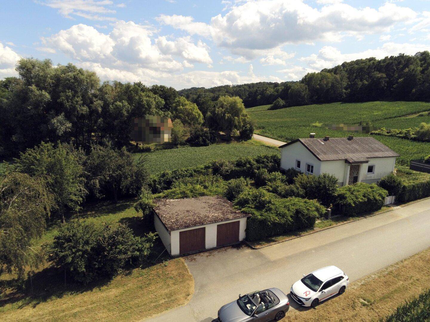 Luftaufnahme des Hauses mit separater Doppelgarage, Straße und weitem Blick ins Grüne.