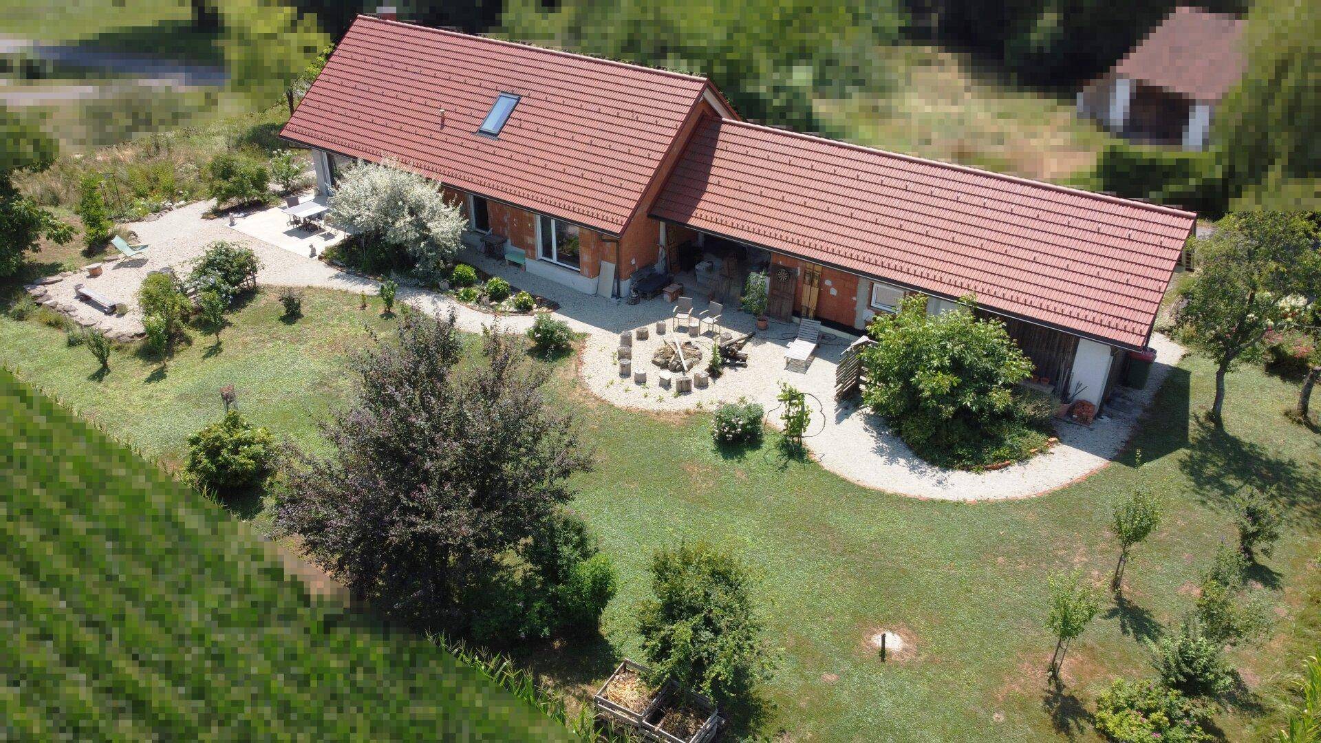 Vogelperspektive des Hauses mit weitläufigem Gartenbereich und gemütlicher Feuerstelle.
