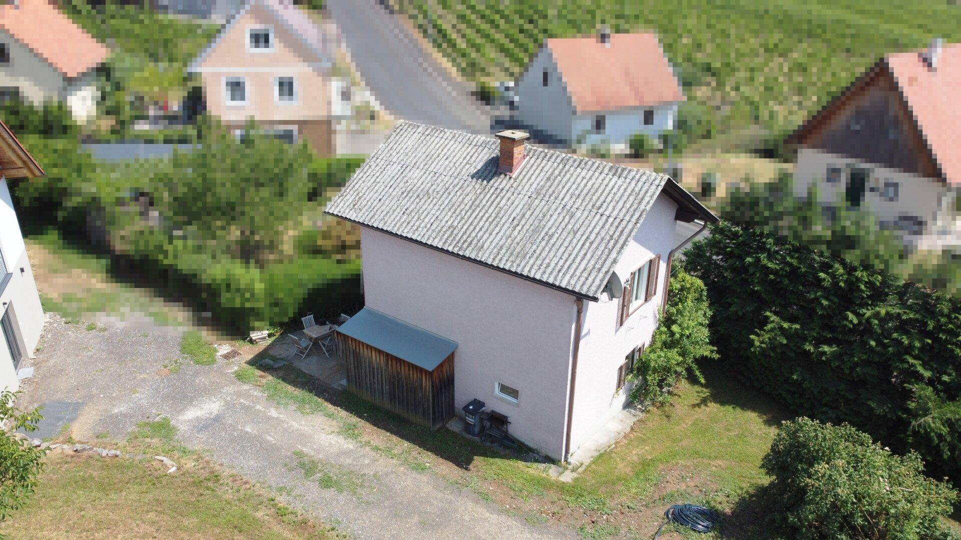 Seitenansicht des Hauses mit angebautem Holzschuppen und Blick auf die umliegende Landschaft.