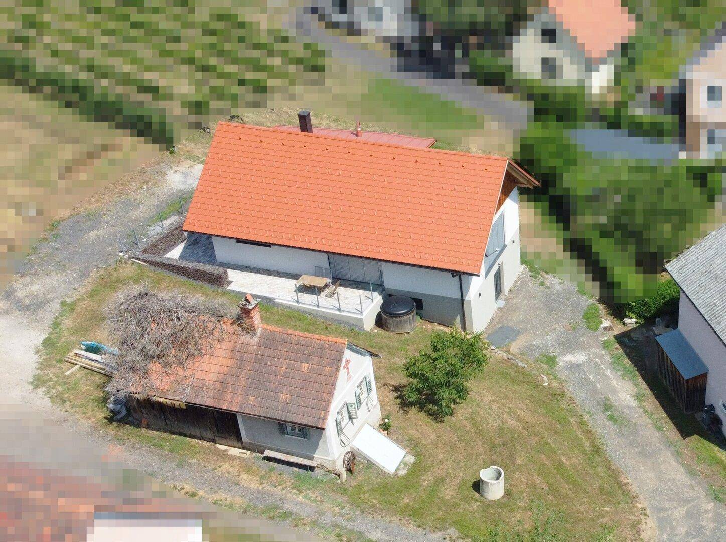 Weitläufige Luftaufnahme der beiden Wohnhäuser in einer idyllischen Weinregion mit weiteren Gebäuden im Hintergrund.