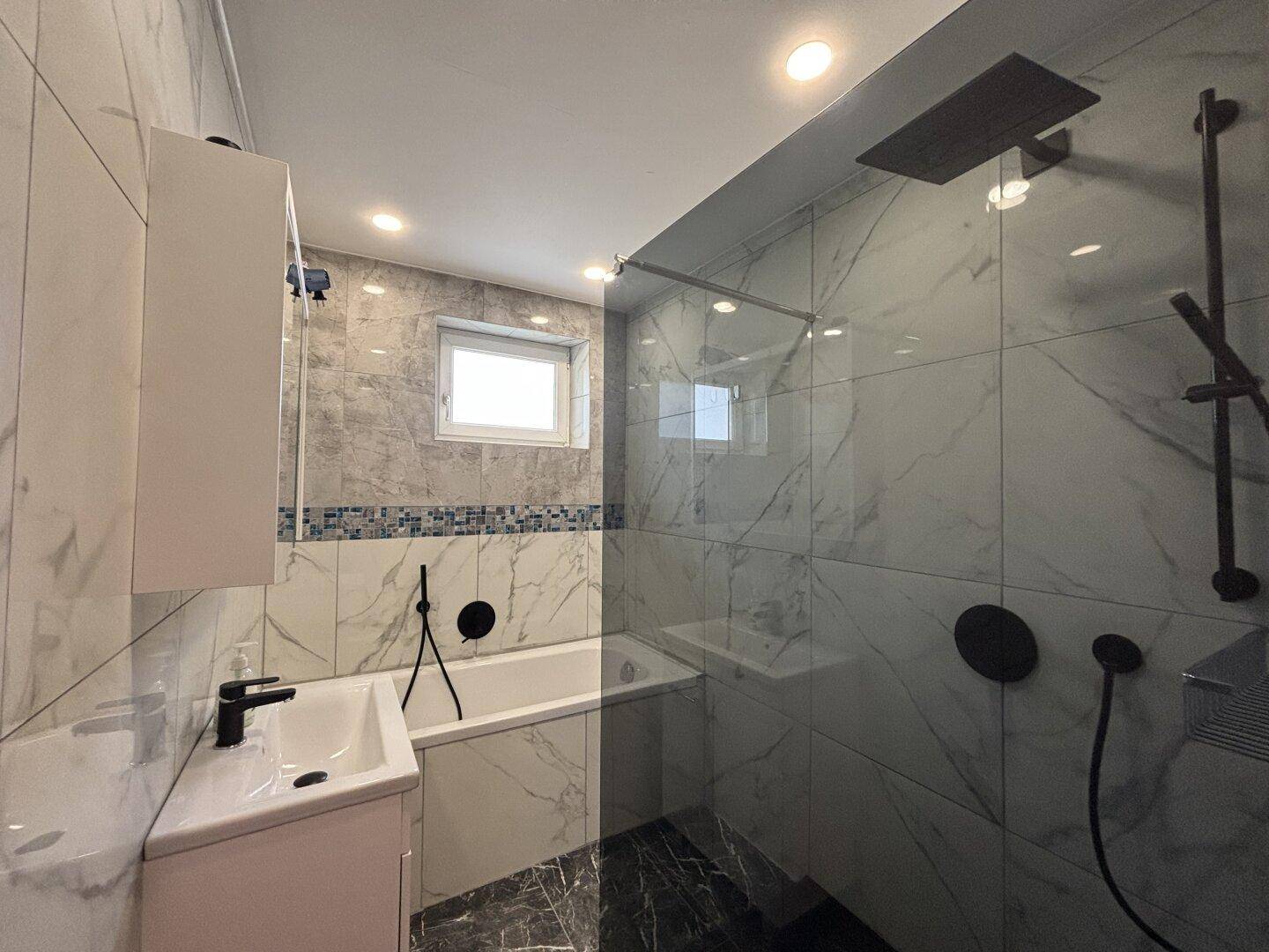 Modernes Badezimmer mit Marmorfliesen, Badewanne und begehbarer Dusche in Schwarz-Weiß.