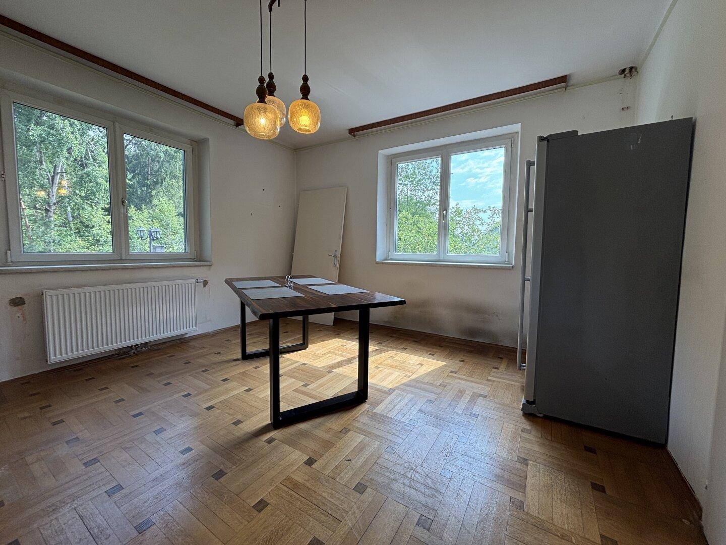 Heller Essbereich mit Holzboden, großzügigen Fenstern und einem modernen Esstisch.