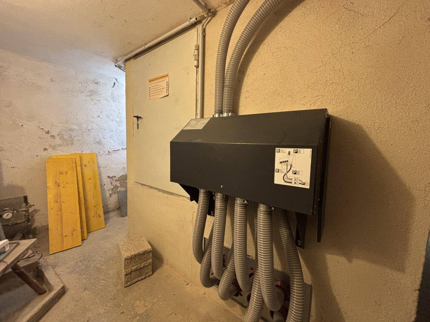 Technikraum im Keller mit elektrischen Installationen und Lagerfläche.