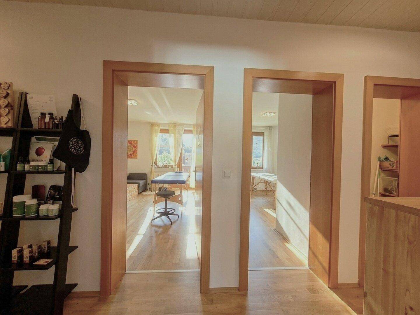 Heller Flur mit Holzfußboden und mehreren Türen, die zu verschiedenen sonnigen Zimmern führen.